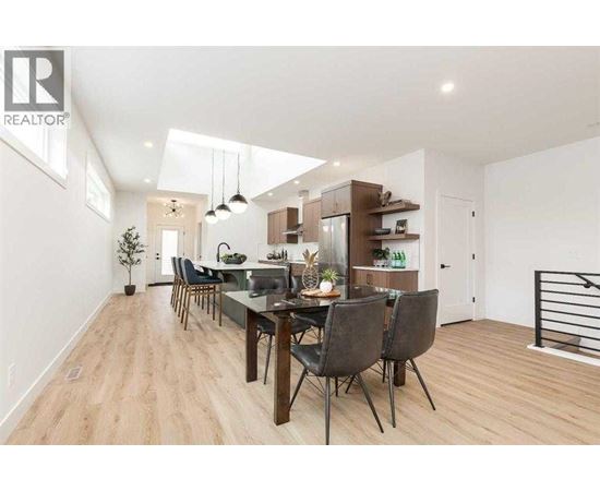 A modern dining room with a wooden floor and a long table with chairs.