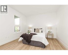 A bedroom with a bed, two lamps, and a window.