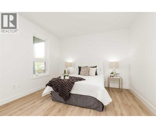 A bedroom with a bed, two lamps, and a window.