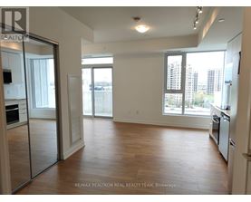 A spacious, empty room with wooden floors and large windows.