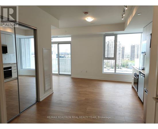 A spacious, empty room with wooden floors and large windows.