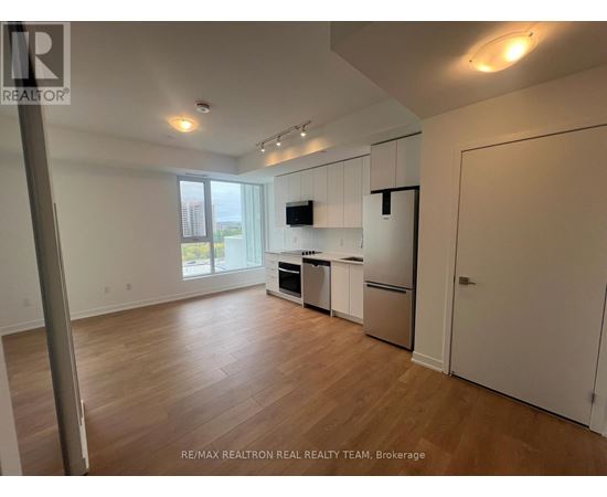 A spacious kitchen with white cabinets and a wooden floor.