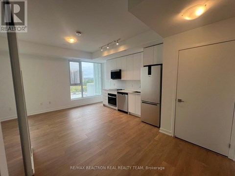 A spacious kitchen with white cabinets and a wooden floor.
