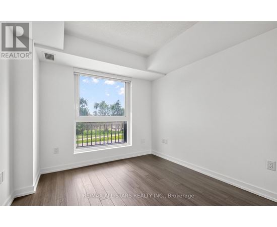 A room with a large window overlooking a fence and trees.