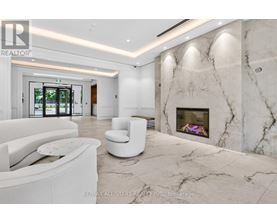 A white living room with a marble fireplace and a large window.