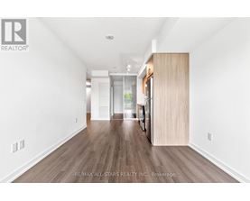 A spacious room with wooden flooring and white walls.