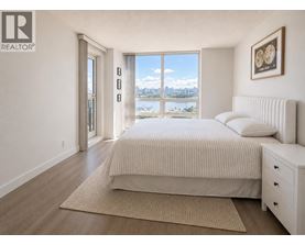 A bedroom with a large bed, a bench, and a view of the city.