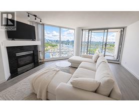 A living room with a fireplace and a large window overlooking a body of water.