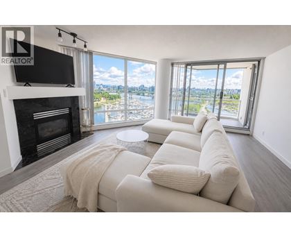 A living room with a fireplace and a large window overlooking a body of water.