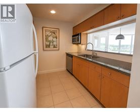 A kitchen with a white fridge, brown cabinets, and a painting on the wall.