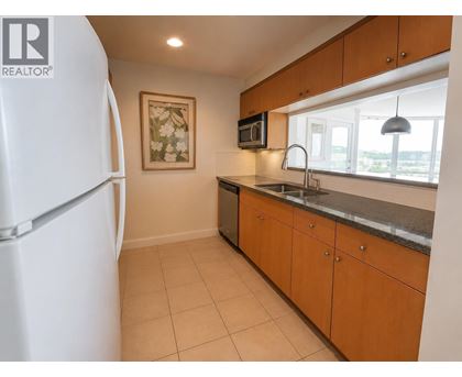 A kitchen with a white fridge, brown cabinets, and a painting on the wall.