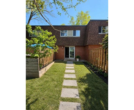 A backyard with a lawn, a wooden fence, and a brick house.