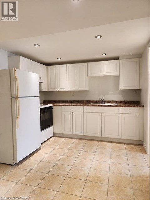 A kitchen with a white refrigerator and cabinets.