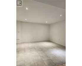 A large empty room with a tiled floor and recessed lighting.