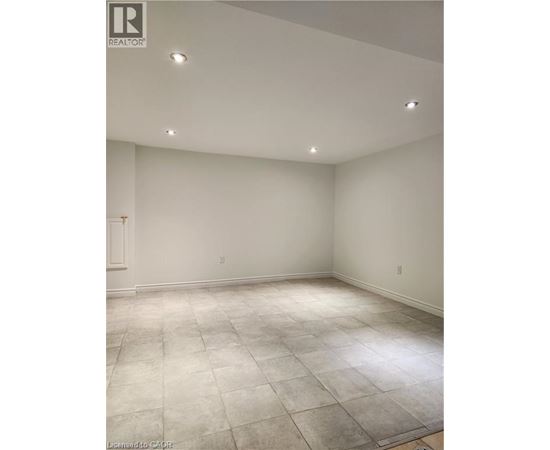 A large empty room with a tiled floor and recessed lighting.