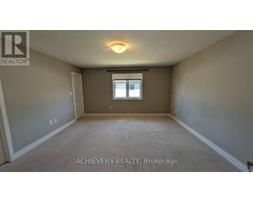 A spacious room with a window and carpeted floor.