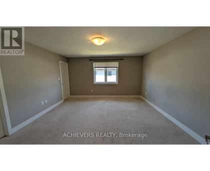 A spacious room with a window and carpeted floor.