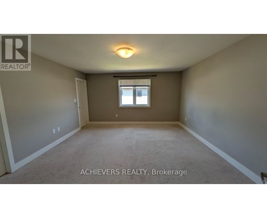 A spacious room with a window and carpeted floor.