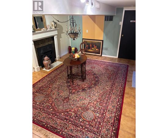 A large oriental rug covers the floor of a room with a fireplace and a chandelier.