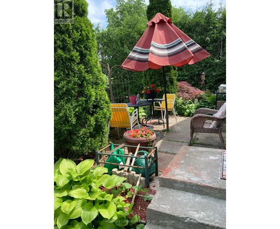 A red and white striped umbrella is open over a table with chairs.