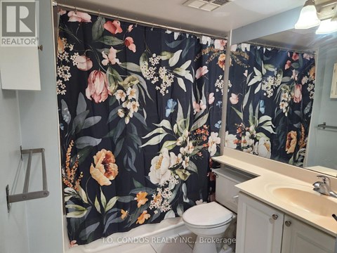 A bathroom with floral shower curtain and a toilet.