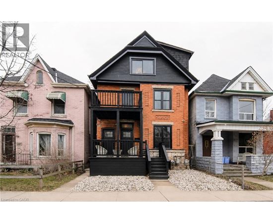 A house with a black front porch and a tree in front.