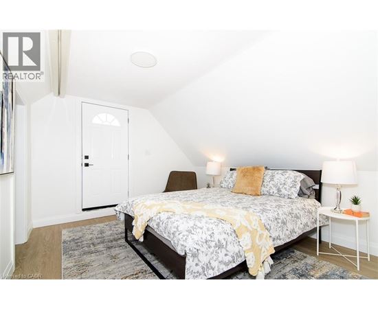 A bedroom with a bed, a nightstand, and a chair.