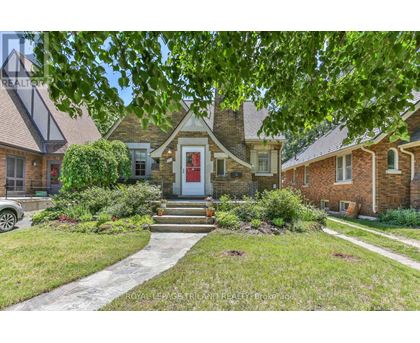 A house with a red door is surrounded by greenery.