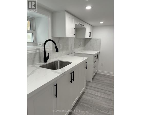 A modern kitchen with white cabinets and a marble countertop.