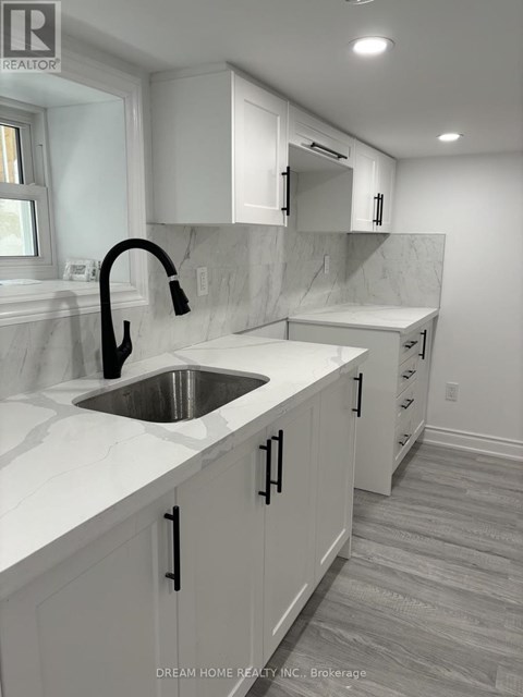 A modern kitchen with white cabinets and a marble countertop.