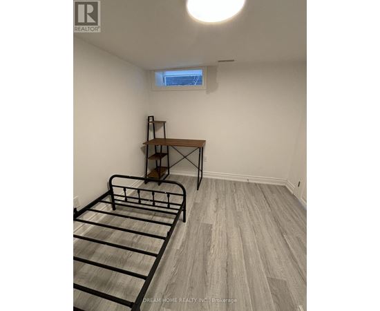 A bedroom with a bed, desk, and window.