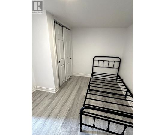A bedroom with a metal frame bed and a wooden floor.