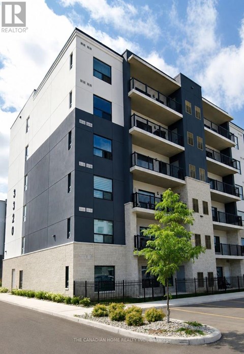 A modern apartment building with balconies and a tree in front.