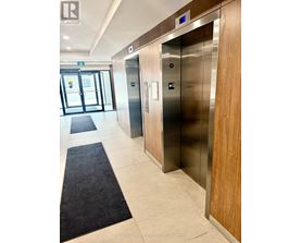 A hallway with two elevators and a door leading outside.