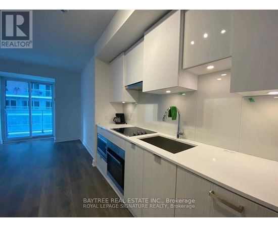 A modern kitchen with white cabinets and a dark floor.