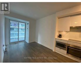 A spacious living room with a kitchenette and a view of the city.