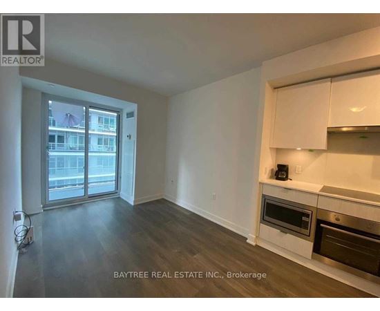 A spacious living room with a kitchenette and a view of the city.