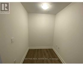 A room with white walls and wooden flooring, with a light fixture on the ceiling.