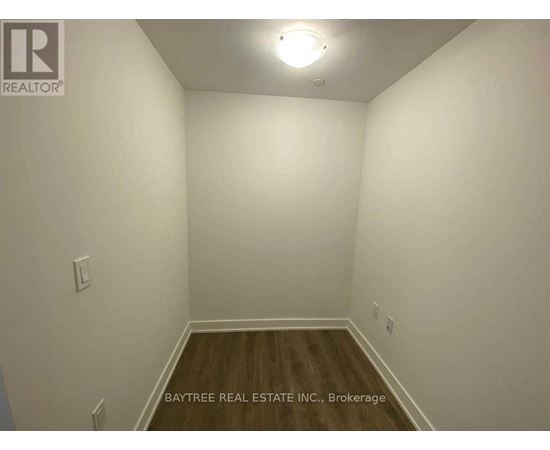 A room with white walls and wooden flooring, with a light fixture on the ceiling.