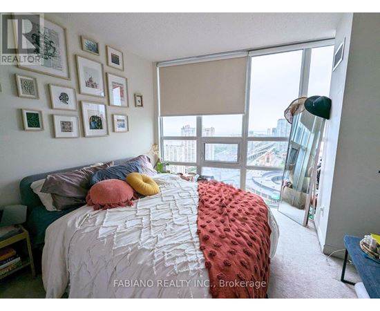 A bedroom with a large bed and a view of the city through the window.