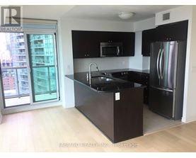 A kitchen with black cabinets and a stainless steel refrigerator.