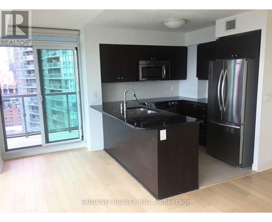 A kitchen with black cabinets and a stainless steel refrigerator.