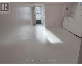 A white room with a refrigerator and a door leading to another room.