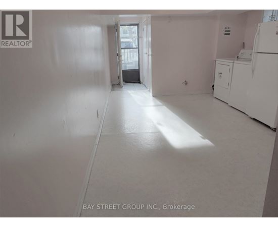 A white room with a refrigerator and a door leading to another room.