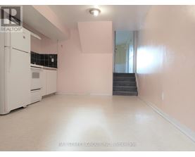 A white fridge in a room with pink walls.