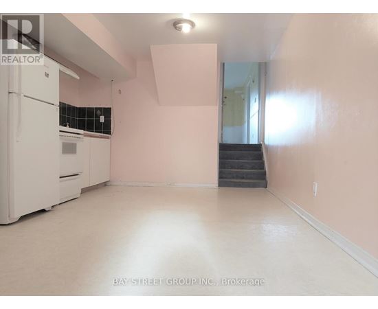 A white fridge in a room with pink walls.