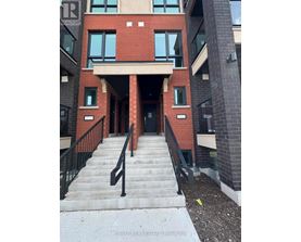 A building with a red brick facade and a black railing on the stairs.