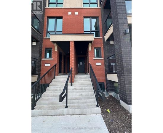 A building with a red brick facade and a black railing on the stairs.