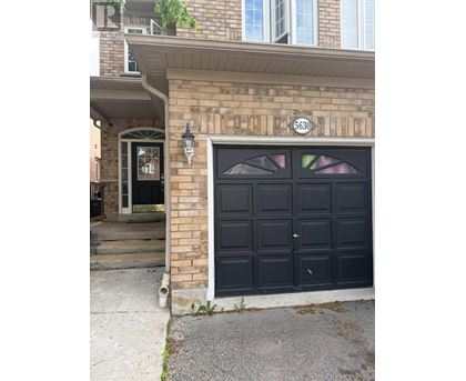 A black garage door with a white number 6630 on the brick wall above it.
