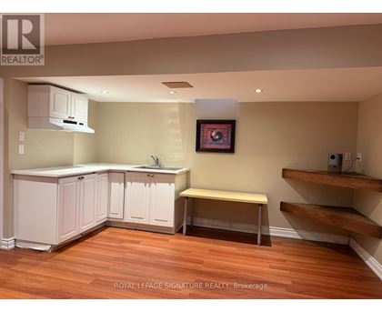 A kitchen with white cabinets and a wooden floor.
